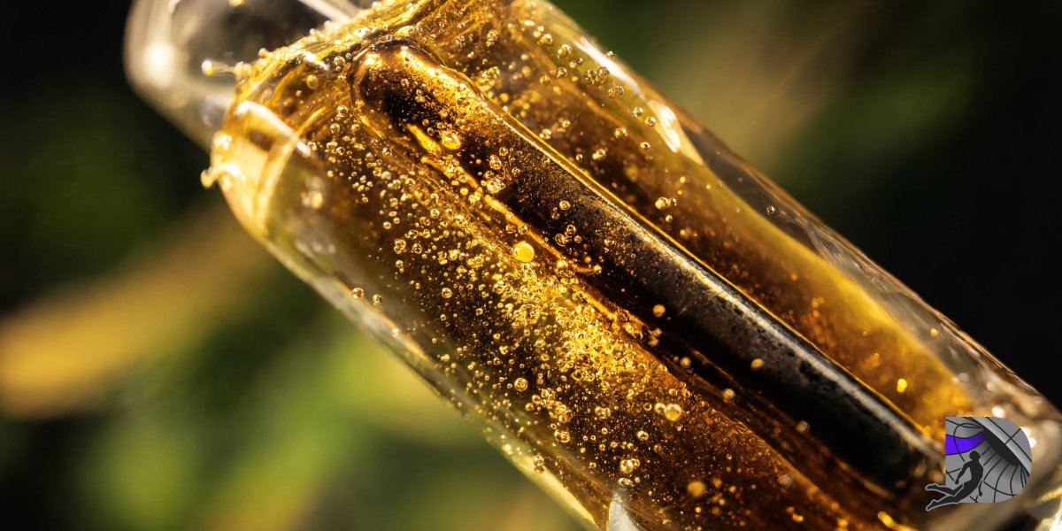 An extreme macro close-up of amber full spectrum live resin vape oil with natural micro-bubbles inside a clear glass cartridge.